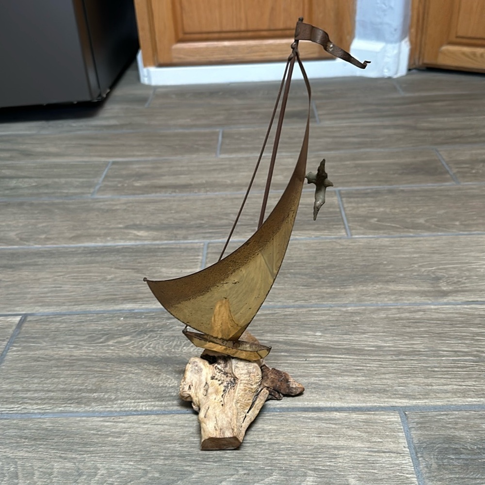 Metal sailboat art piece on driftwood base. Sail has flag and bird attached. 70s